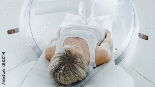 Female Patient Lying on a CT or MRI Scan, Bed is Moving inside Machine Scanning Her Body and Brain. In Medical Laboratory with High-Tech Equipment.