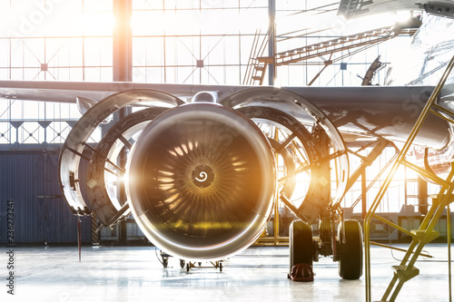 Opened hood airplane engine jet under maintenance in the hangar ,with bright light flare at the gate.