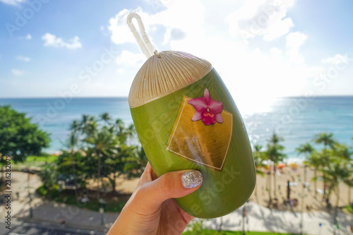 hand grabbed a coconut-shaped container on the background of waikiki beach, O'ahu, Hawaii