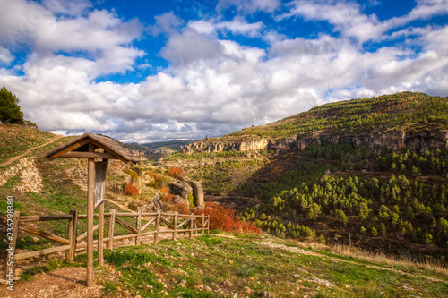 A beautiful landscape with blue sky, white clouds and mountains and a path with a nonspecific national forest type sign in the foreground