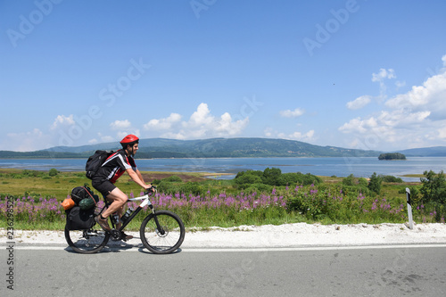 Cyclist with a saddle bag near a lake. Traveler on bicycle on sunny day