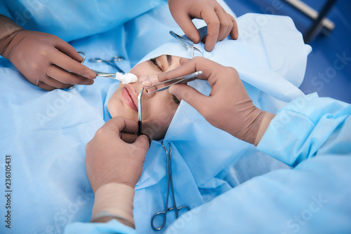 Top view photo of medical operation. Surgeon holding forceps while second doctor using tool with cotton wool