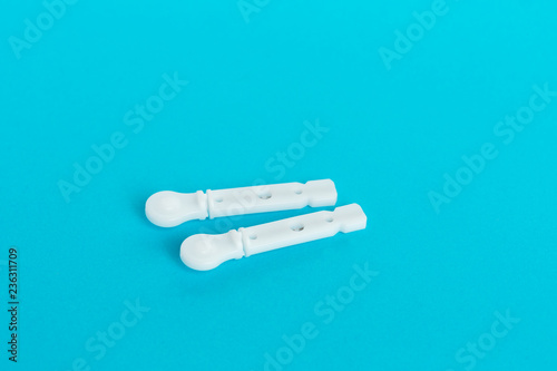 White lancet needle for a glucometer lies on a blue background