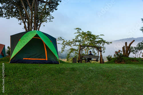camping tent on the meadow field on mountain and old camper sitting on wooden swing