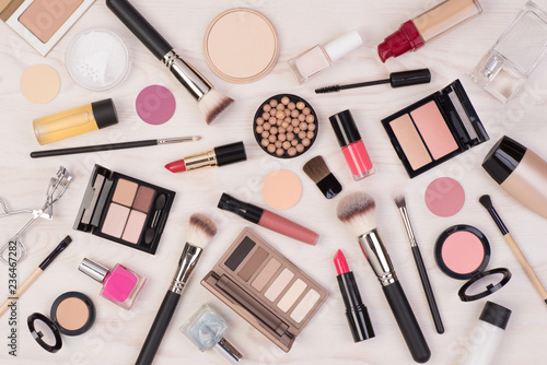 Makeup cosmetics such as eyeshadows, lipstick, mascara and makeup accessories on white, wooden background, top view