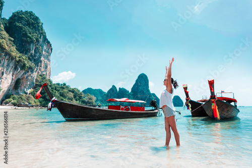 Young woman with thailand longtail boats on beach
