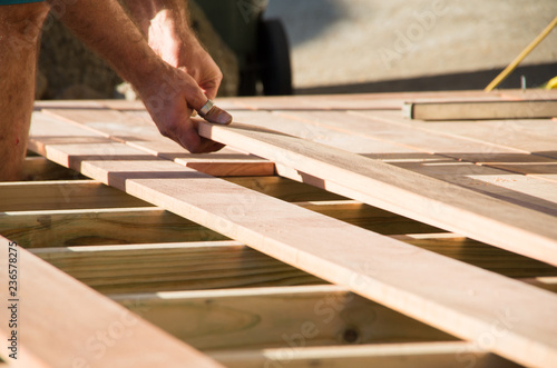 Man placing a plank of wood in a deck home renovation