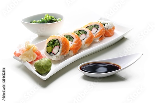 Tradycyjne japońskie sushi z łososiem podane na talerzu z sosem sojowym i zieloną sałatką z trawy morskiej