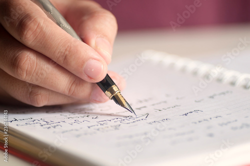 Close up of female hands with pen writing on notebook