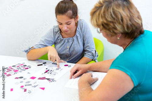Therapist working with a teenage girl with learning difficulties to master logical tests.