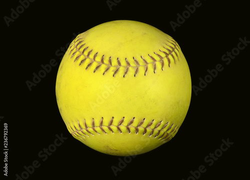 closeup of neon yellow softball with red stitching isolated on black