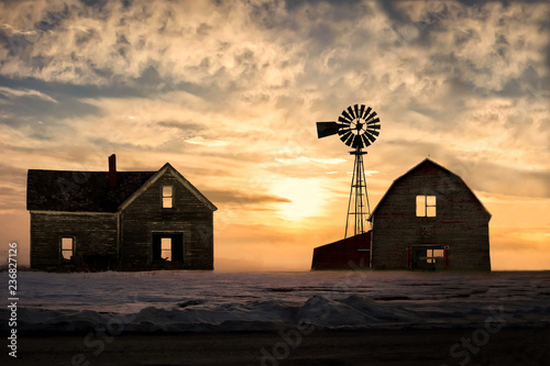 old abandoned silhoetted house and barn with beautiful sunset