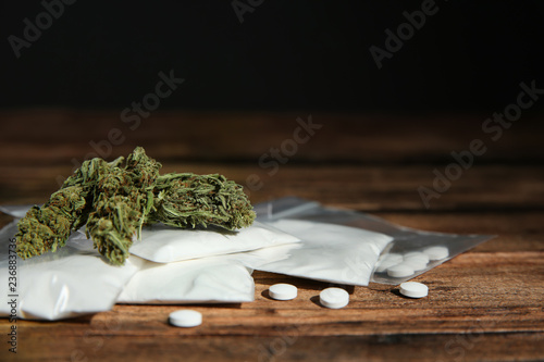 Cocaine, dried hemp and ecstasy on wooden table. Space for text