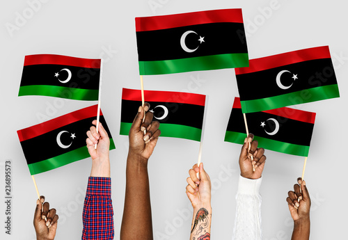 Hands waving flags of Libya