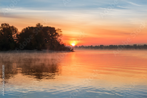 Sunrise over the plain river at autumn
