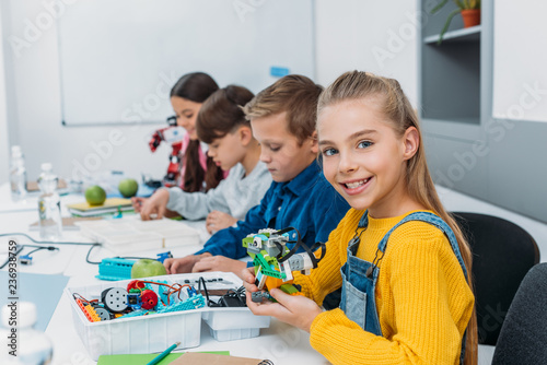 cheerful classmates making a robot during STEM robotics class