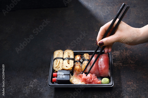 Sushi lunch. Pudełko z sushi .Jedzenie sushi pałeczkami prosto z tacki.