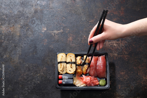 Obiad na wynos, tacka sushi. Jedzenie sushi pałeczkami prosto z tacki.