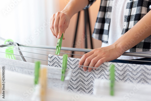 Woman hanging wet clothes with clothespins