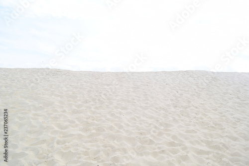 Background of white sand and the light sky. Texture.