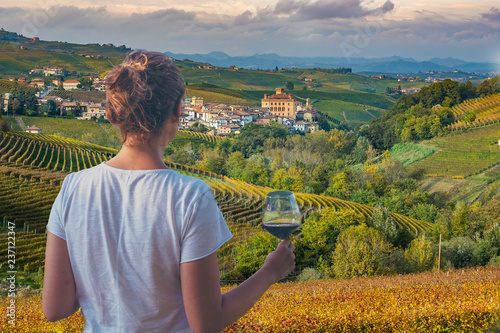 girl holding a glass of red wine looking amazing green vineyards in the italian region of Piedmont, Alba, Barolo town, langhe Monferrato region, Italy