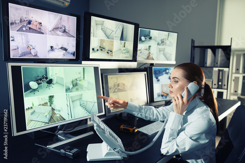 Security guard monitoring modern CCTV cameras in surveillance room