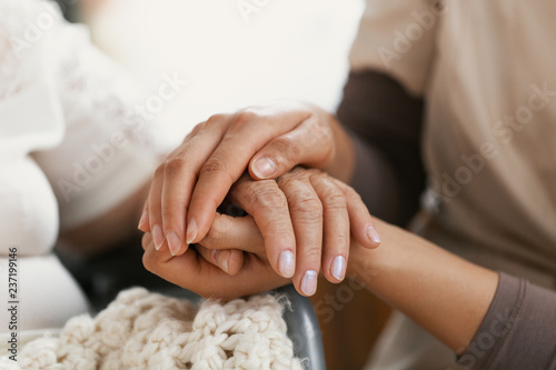 Closeup of hands of a young woman holding hand of an senior lady