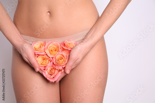 Sexy young woman holding roses near her panties, closeup. Erotic concept