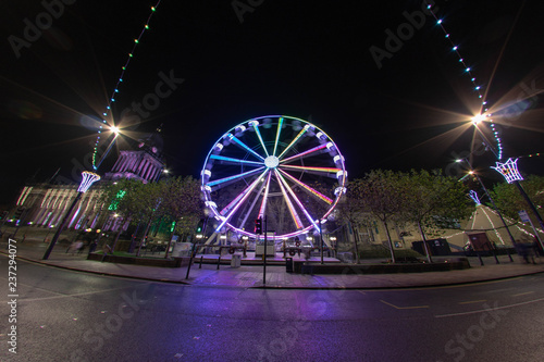 Long exposure Wide Angle photo of the Leeds Christmas ferris wheel that is outside the Leeds Town Hall and Leeds Library in the Leeds City Center West Yorkshire UK