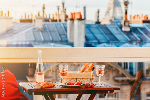 Paris luxury lifestyle. Pink wine in two glasses, traditional french bakery products and strawberries on a balcony