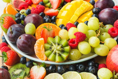 Assorted fruits and berries platter, strawberries blueberries, mango orange, apple, grapes, kiwis background, selective focus