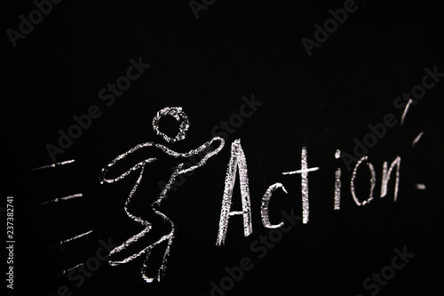 drawn in chalk on a black blackboard the symbol of the running man and the word action