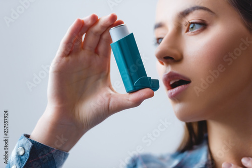 close-up view of young woman with asthma using inhaler