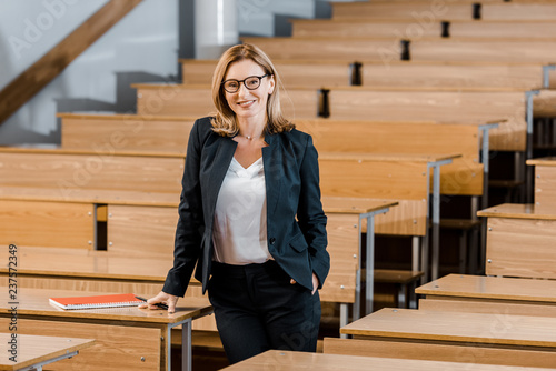 beautiful female university professor smiling and looking at camera in classroom