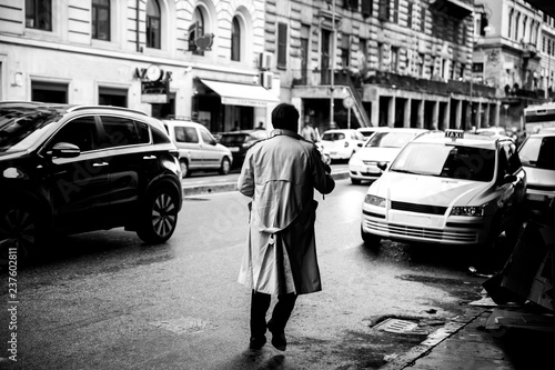 a man wearing a gabardine crossing the street