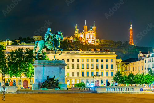 Night view of Basilica Notre-Dame de Fourviere viewed behind statue of Louis XIV in Lyon, France