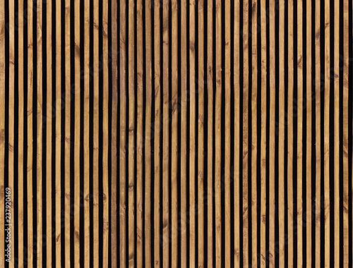 Seamless pattern of modern wall paneling with vertical wooden slats for background. Raw material of natural brown wood lath.