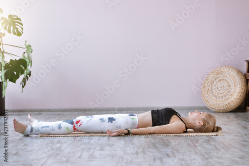 Young woman practicing in a yoga studio. Shavasana or corps pose is the end of a class or practice.