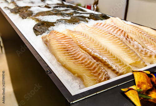 Split cod fillet lying on the ice on the counter of the fish store