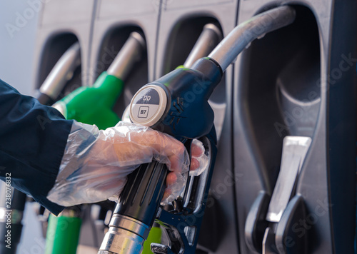 Fuel pistols at european Petrol station. Woman's hand in plastic glove taking Diesel fuel pistol. Focus on the DD & B7 letters. Diesel rate increase.