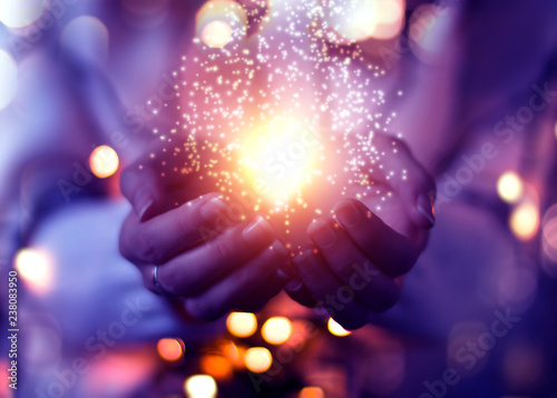 Magic particles emanating from female hands. Christmas background with bokeh