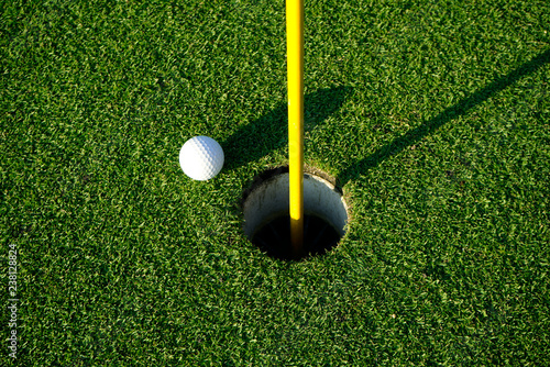 Golf ball on the edge of hole on the green grass