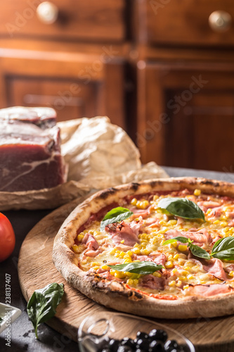 Italian pizza cardinale with ham prosciutto tomatoes corn and basil