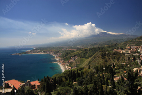 dymiący wulkan etna na sycylii z pięknym niebieskim morzem, plażą i miasteczkiem w tle w słoneczny dzień