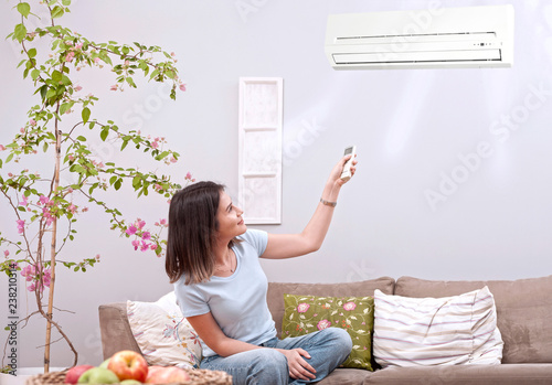 woman using remote control of aircondition 