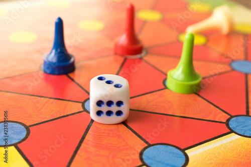 Multi-colored game chips with dice on the playing board. Board game