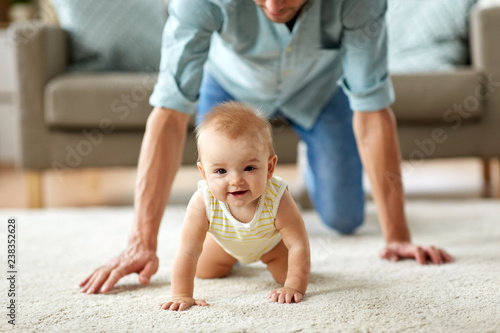 family, fatherhood and parenthood concept - happy little baby girl with father at home crawling on floor