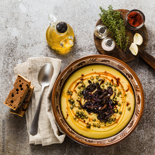 Authentic Greek Fava recipe, Middle Eastern yellow lentil soup with caramelized onions, paprika and capers. vegan healthy food in clay pots on the stone table