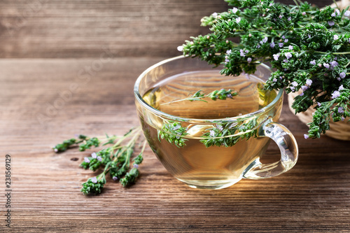 Herbal tea with thyme over rustic wooden background.