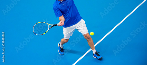 man playing tennis on blue floor